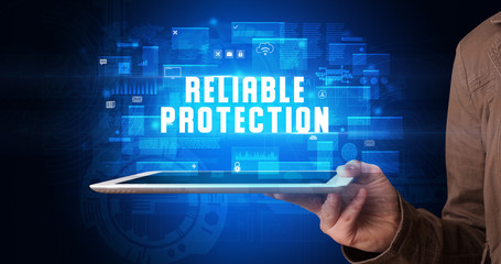 Young business person working on tablet and shows the digital sign: RELIABLE PROTECTION