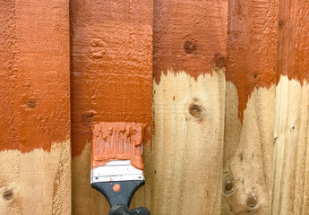 Close up of a wooden fence panel being painted with fence paint. No people