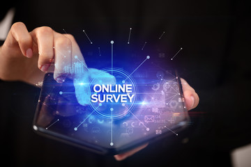 Businessman holding a foldable smartphone with ONLINE SURVEY inscription, new business concept