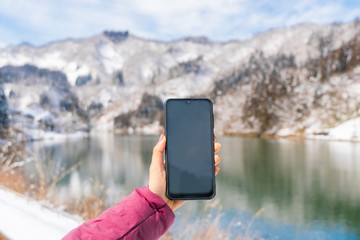 Female hand holding smart phone with blank screen for copy space, close up, winter with snow...