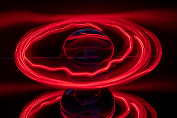 some red rings surround a crystal clear glass ball on a mirror