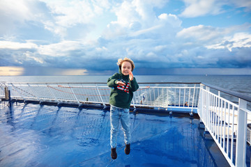 smiling kid having fun on the upper deck of cruise ship after heavy rain storm on the sea during vacation