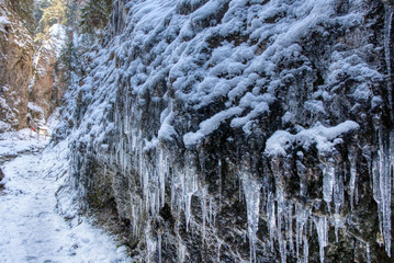 frozen stalactites on rocks in mountains with snow around, slovakia mala fatra