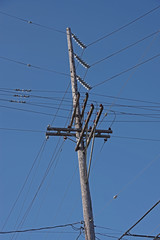 Low angle view of an electrical distribution pylon and wires under a deep blue sky
