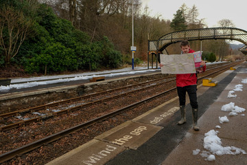 Man at a Country Train Station with a map - Adventure is out there!