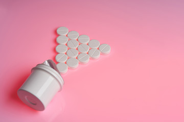 White round tablets scattered near plastic bottle of pills