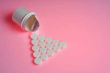 Pile of white pills on pink background