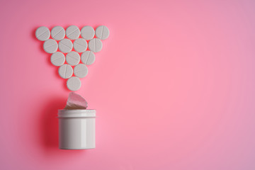 pills and pill bottle on pink background
