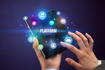 Businessman holding a foldable smartphone with PLATFORM inscription, social media concept