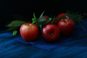 manzanas rojas, sobre un fondo azul con una rama de romero y hierba buena