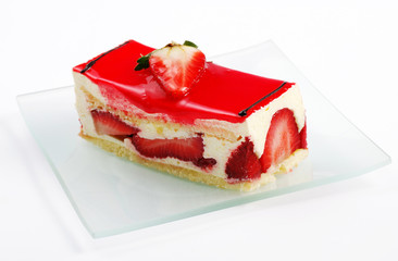 Strawberry cake full of fruits on transparent glass plate, close-up view, white background