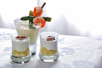 Gourmet appetizers served in small glasses on white elegant napkin.