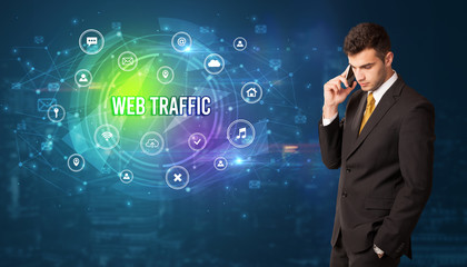Businessman thinking in front of technology related icons and WEB TRAFFIC inscription, modern technology concept