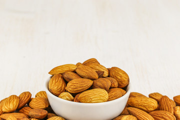 Almonds in a white bowl and on a white background