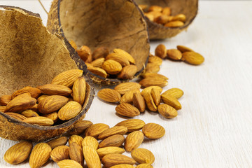 Almonds in half a coconut shell and on a white background