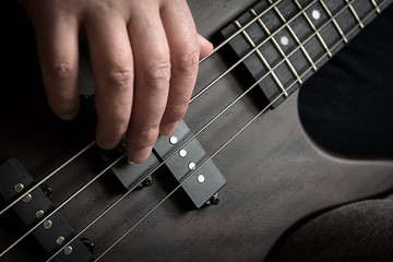 Bass guitar player hand closeup, lesson and practice theme. Playing rock on bass electric guitar,...