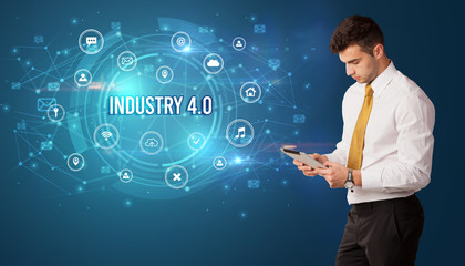 Businessman thinking in front of technology related icons and INDUSTRY 4.0 inscription, modern technology concept