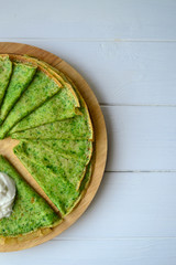Green spinach pancakes on a wooden board. Traditional thin pancakes for Maslenitsa.