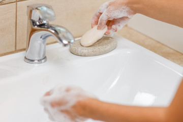 a Washing hands with soap under the faucet with water