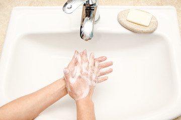 a Washing hands with soap under the faucet with water