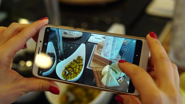 A woman is photographing a plate of salads in a buffet restaurant. Social network blogger concept photo. Healthy and tasty food.