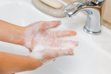 a Washing hands with soap under the faucet with water