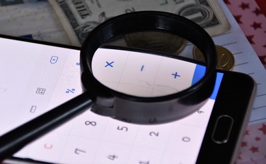 1 dollar bill, euro cents, magnifier and calculator in a smartphone