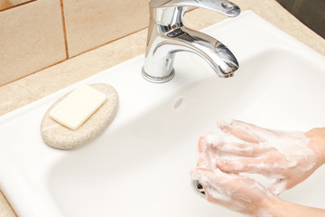 a Washing hands with soap under the faucet with water
