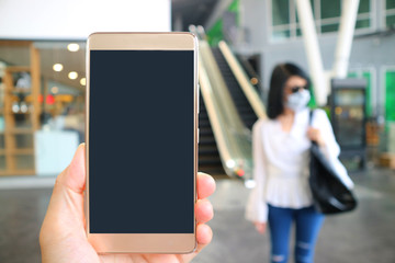 Closeup blank mobile phone screen with blurry woman wearing face mask prevent the flu