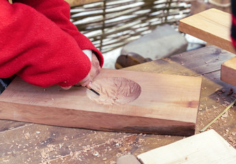 Wood carver craftsman carves a snowflake on a board.