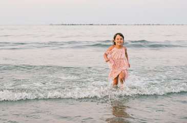 Little girl with pink dress having fun in sea water