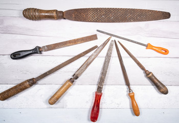 Sets of different wood rasps of different sizes in the middle of an old wooden floor background. top view