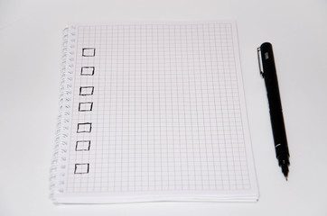 Check list. Square items are empty and checked with a tick. Squared notebook with black pen on a white background. Record ideas, notes, plans, tasks.  Copy Space