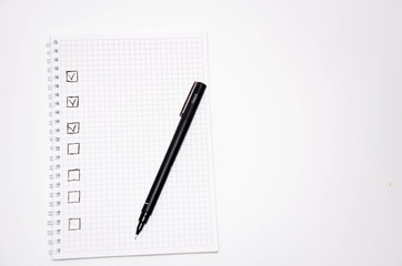 Check list. Square items are empty and checked with a tick. Squared notebook with black pen on a white background. Record ideas, notes, plans, tasks.  Copy Space