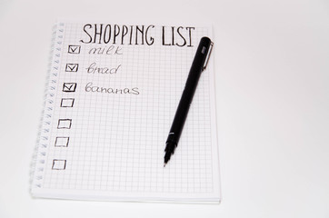 Shopping list. Squared notebook with black pen on a white background. Record ideas, notes, plans,...