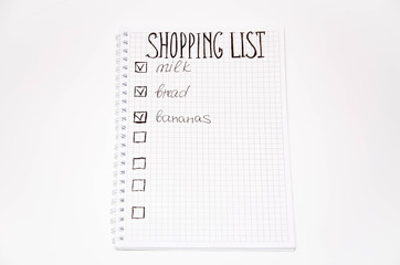 Shopping list. Squared notebook with black pen on a white background. Record ideas, notes, plans, tasks. The list includes bread, milk, bananas.  Copy Spase