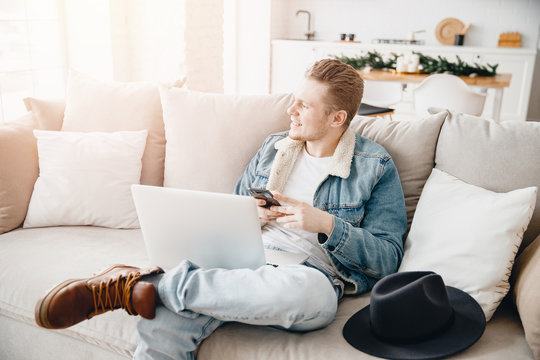 Happy young businessman using laptop at home in living room. Concept freelance dreams startup, personal growth development