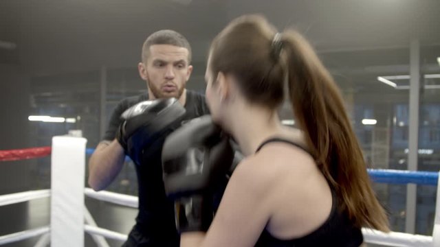 Young woman boxing with coach in gym
