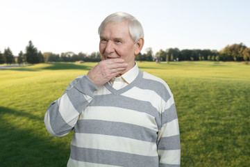 Pensive happy man outdoor. Senior thinking in lawn background.