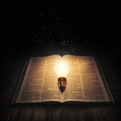 Light bulb lighting up an open bible
