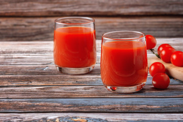 Two glasses of tomato juice on a wooden table, on a wood background, fresh drink