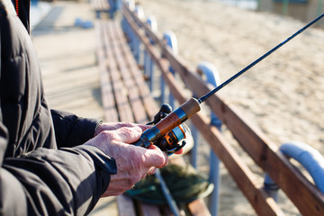 Fishing rod in the hands of a fisherman on the lake. Fisherman's hands with spinning on the background of water