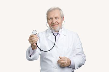 Old doctor using stethoscope. Portrait of a physician holding a stethoscope in white isolated background.