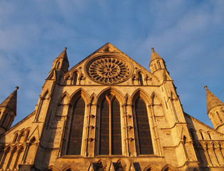 a side view of york minster in sunlight against a blue cloudy sky