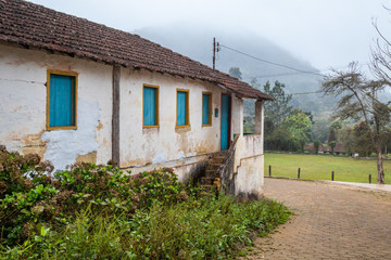 Fototapeta na wymiar Winter landscape with rustic house of old architecture on cold and rainy day in rural location of Brazil.