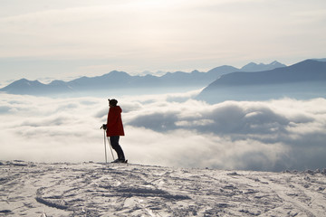 Fototapeta na wymiar Skier on top of the snowy mountains, above the clouds, sunset sun. Caucasus mountains in winter, Georgia, Gudauri region.