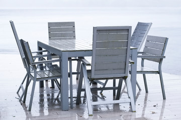 Wet British weather summer outdoor seat and table on decking in rain by lake at holiday home Loch Lomond