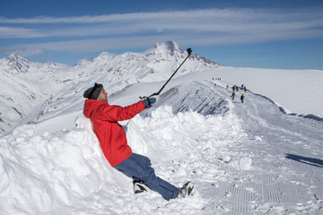 Fototapeta na wymiar Skier makes photo on top of snowy mountain at nice sun day. Caucasus Mountains in winter, Georgia, region Gudauri.