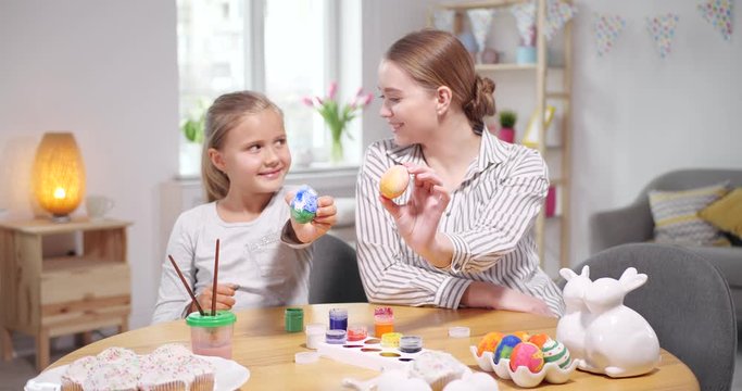 Happy mother and daughter with painted Easter eggs at home