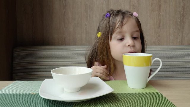 Beautiful cute little child, baby gerl, drink tea. Kid having breakfast.